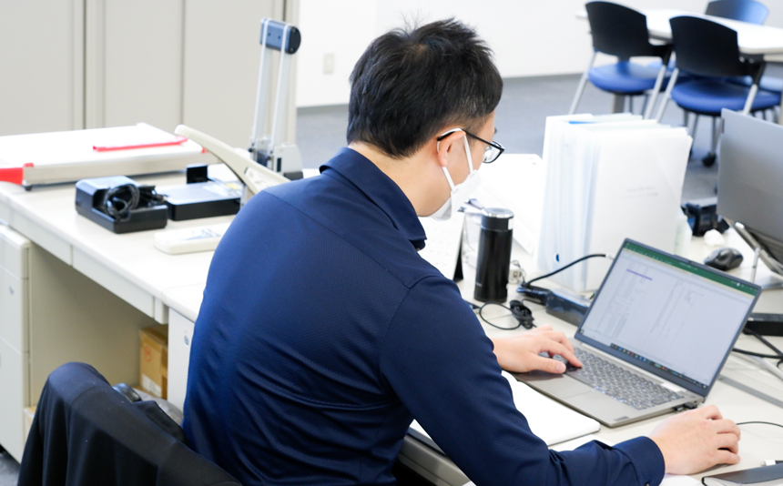 海外営業担当の社員がパソコン業務を行う後ろ姿。